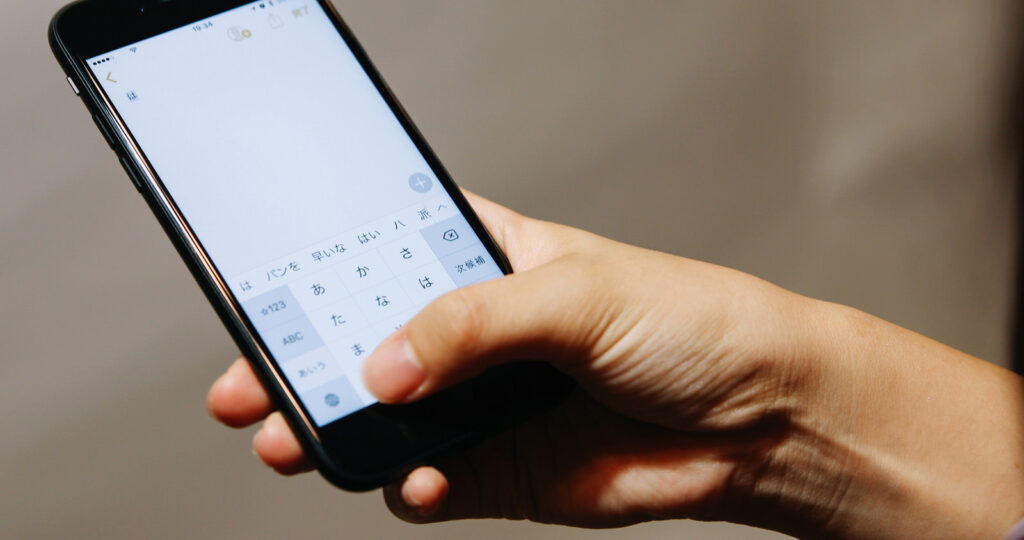 スマホを手に、問い合わせフォームへ文字を入力している手元の様子