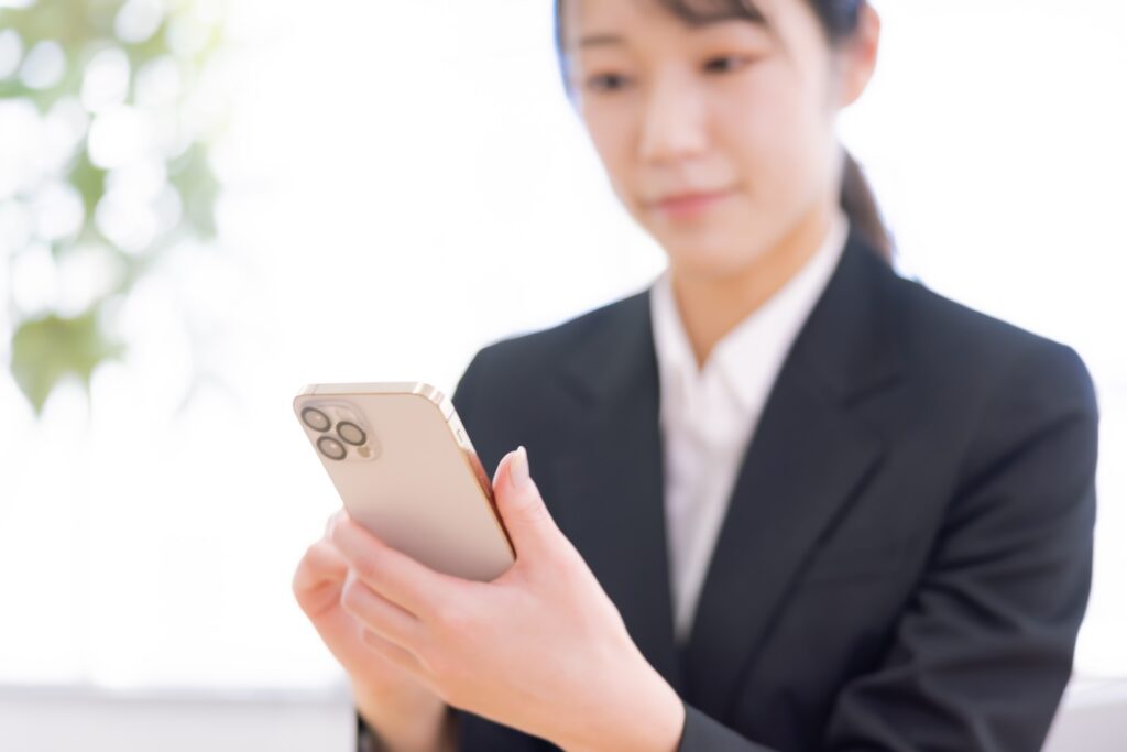 スマートフォンを手に持ち、AIに質問を入力しようとしている手元