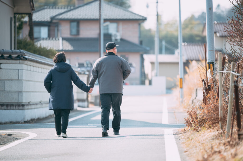 住宅地を並んで歩く夫婦の後ろ姿。住まいの工事は家族で時間をかけて考える