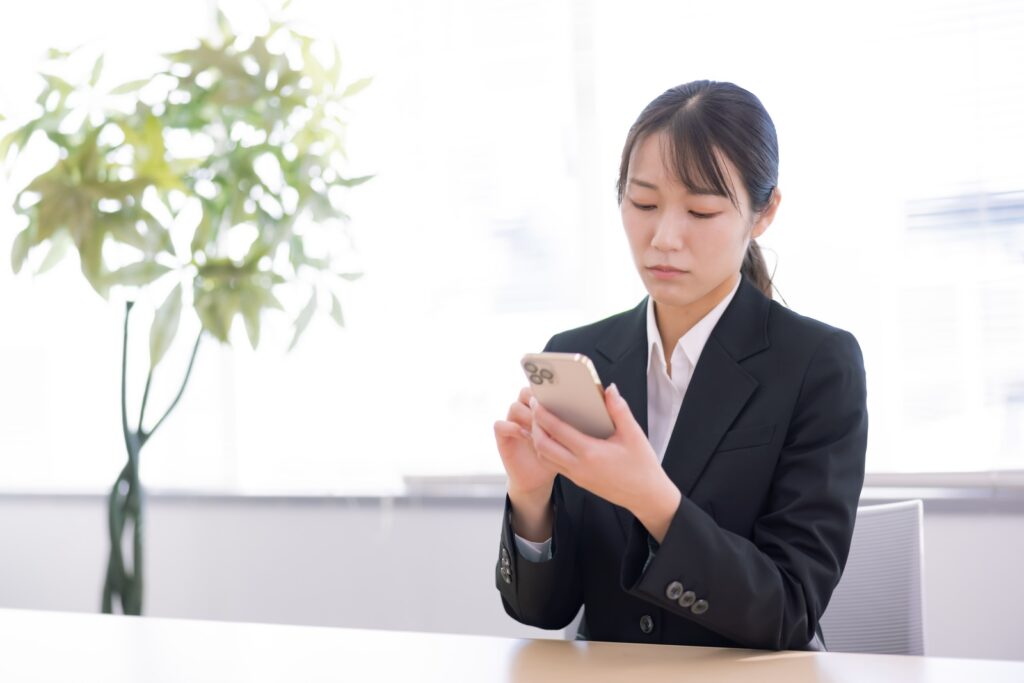 机でスマホを見ながら、新しい言葉の営業を受けて考え込んでいる店主の手元