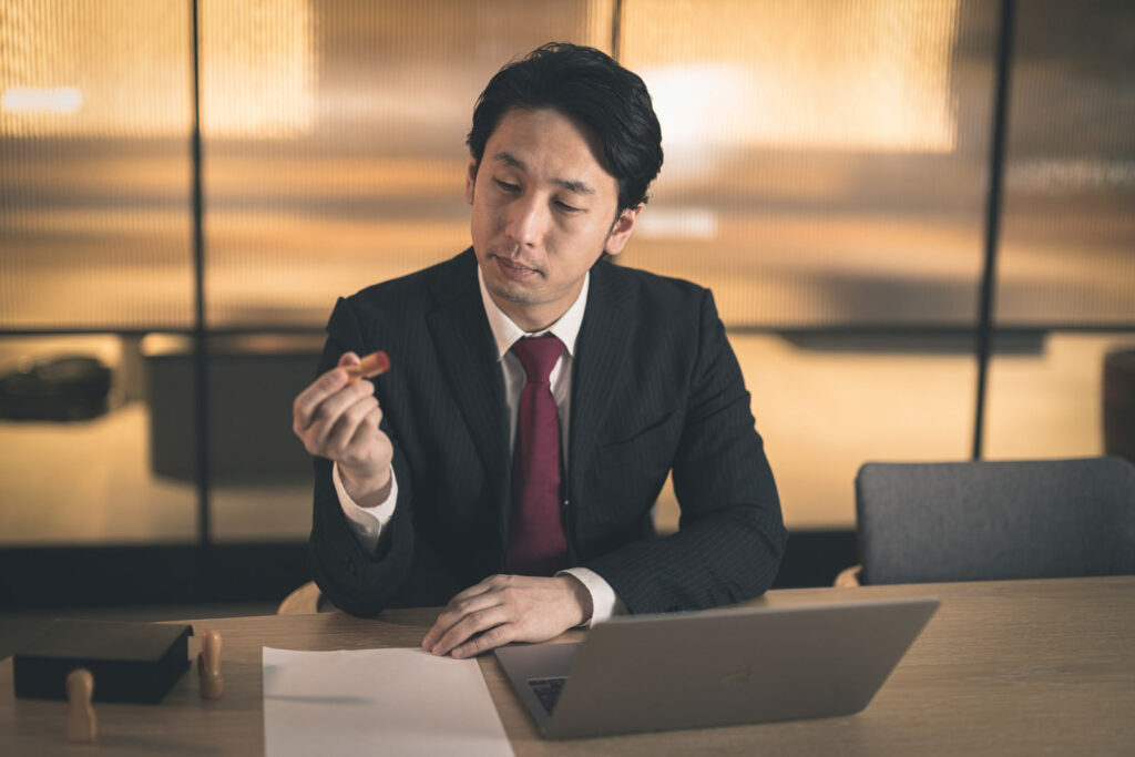 机の上で契約書を見ながら、ノートパソコンで契約の内容を確かめている手元